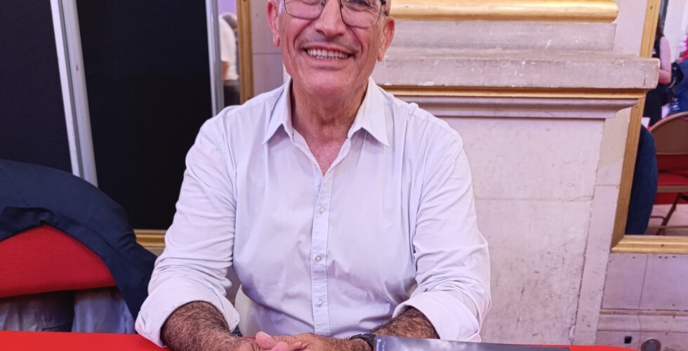 Toufik Hedna assis au stand des Éditions Hedna, lors du Maghreb des livres 2025 à Paris.